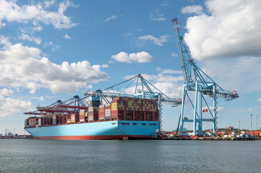 Ett stort containerfartyg i lasthamn sett från aktern