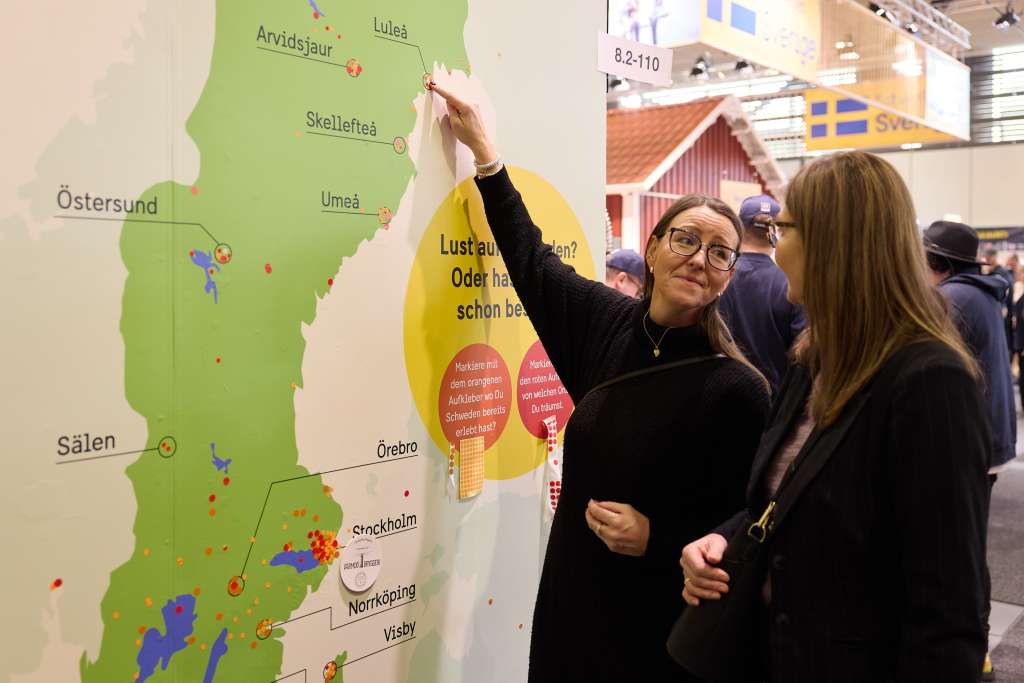 Två kvinnor pekar på en Sverigekarta.